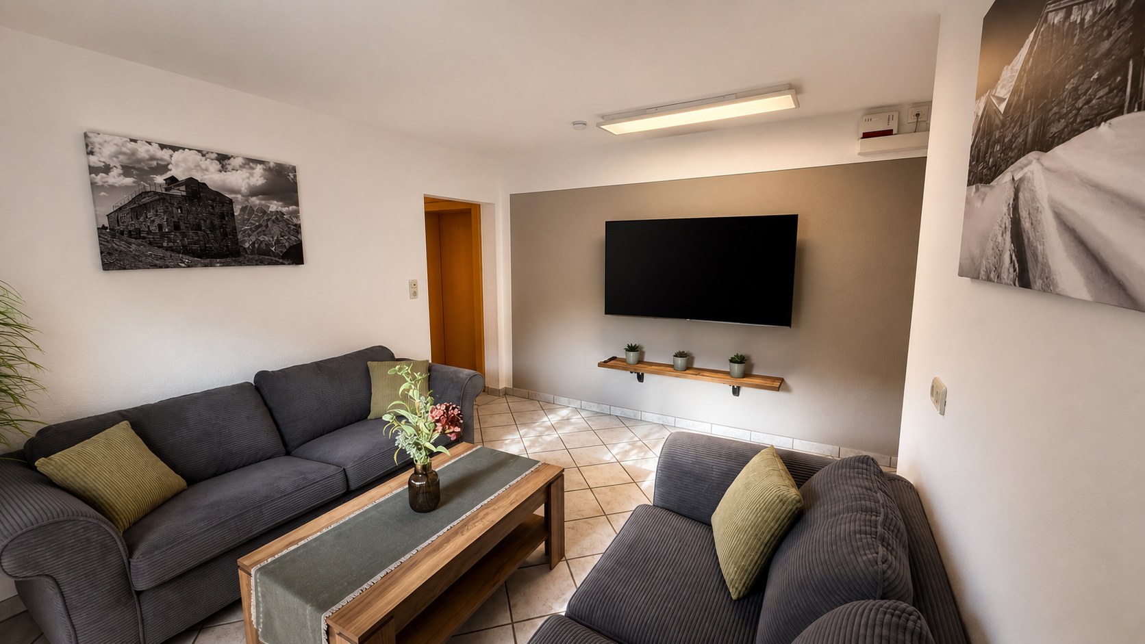 Wohnzimmer der Ferienwohnung mit zwei Sitzbereichen, Couchtisch und Smart-TV